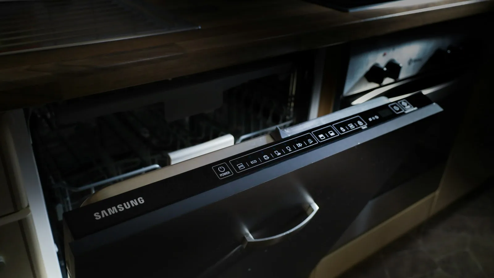 A dishwasher with its control panel visible along the top edge of the open door