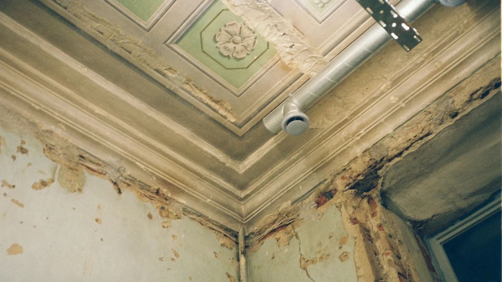 Water-stained, peeling ceiling corner damaged by a leak