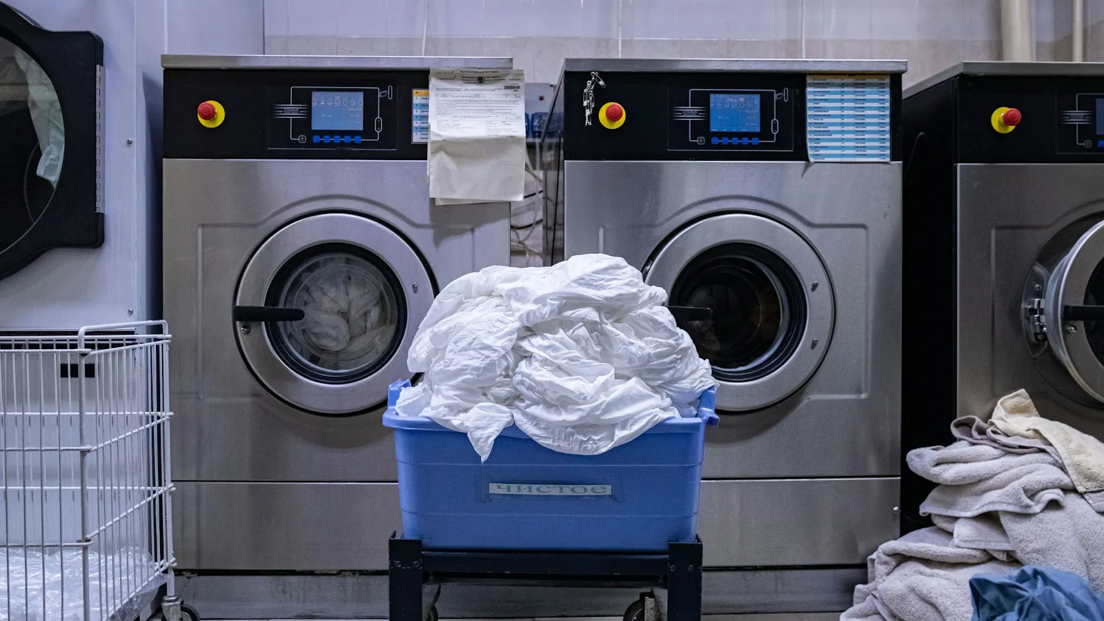 Laundry room with commercial washers and a basket of towels