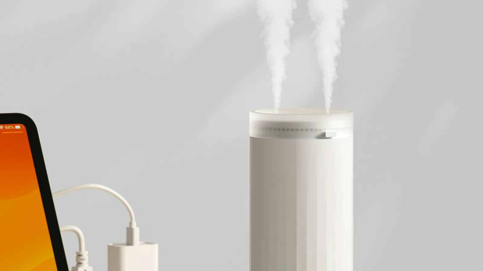 White humidifier releasing mist on a wooden desk