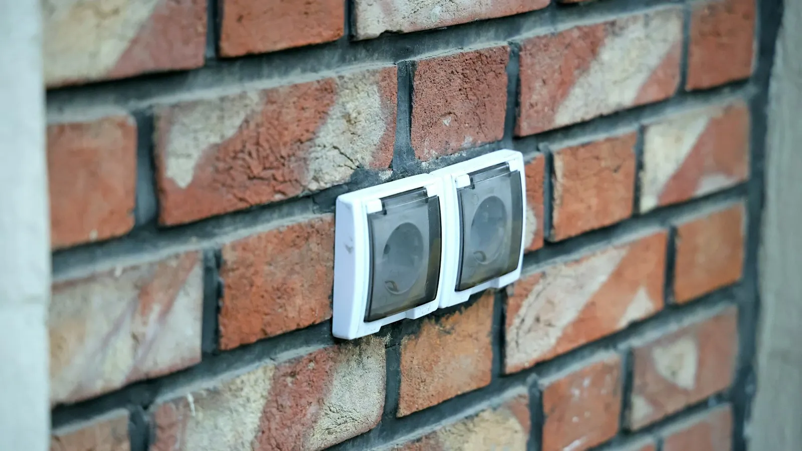Electrical outlet mounted on an exterior brick wall