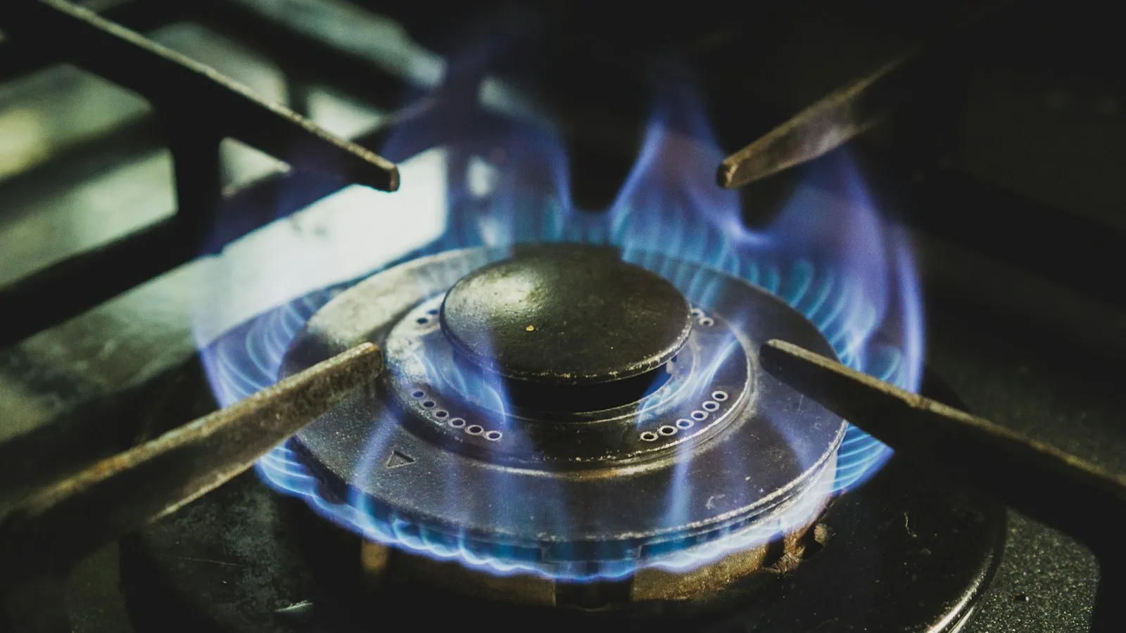 A gas burner lit with a blue flame on a stove top