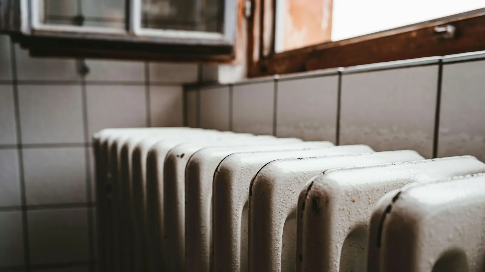 Old white cast iron radiator under a window