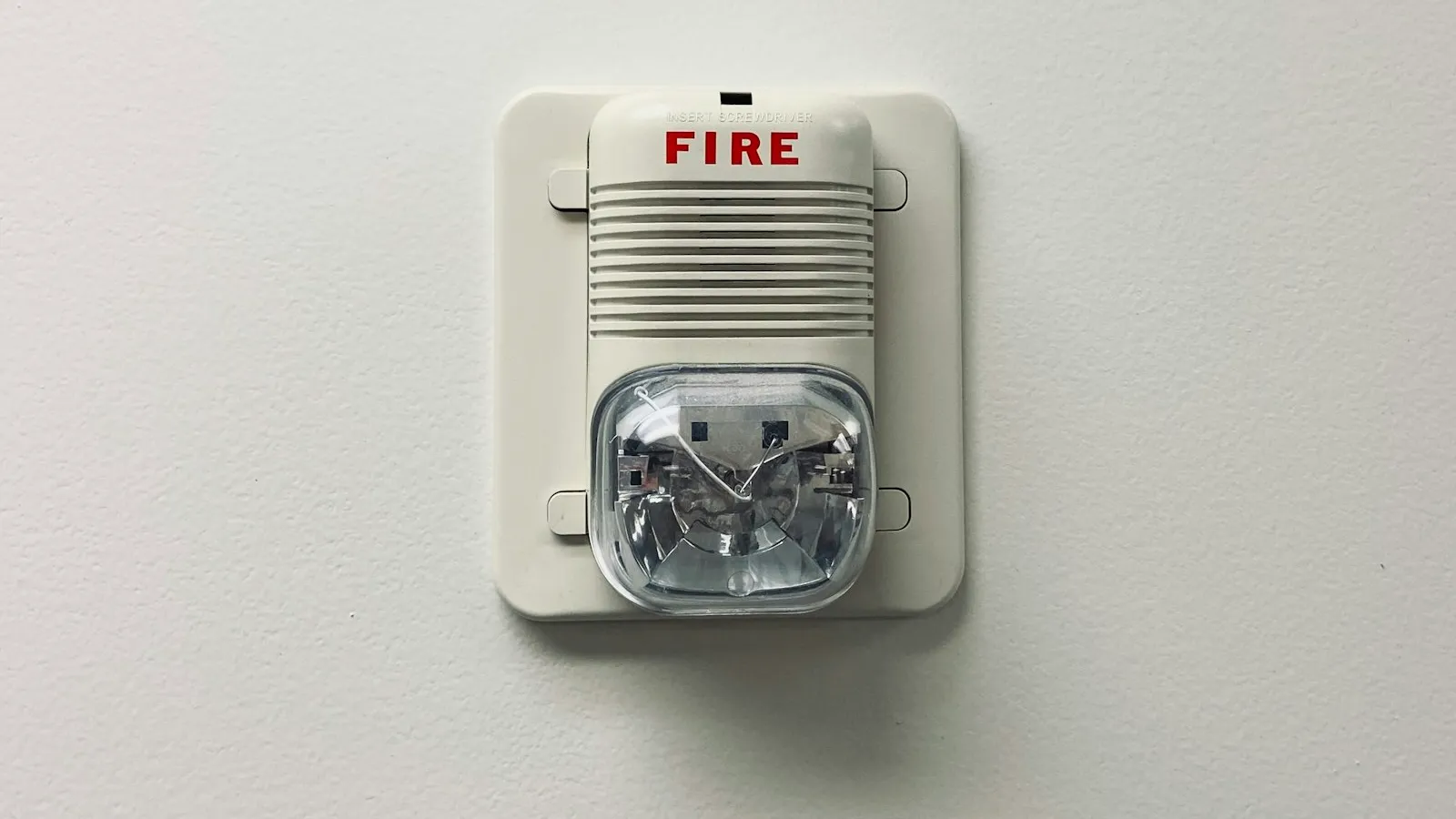 Fire alarm horn and strobe mounted on a white wall