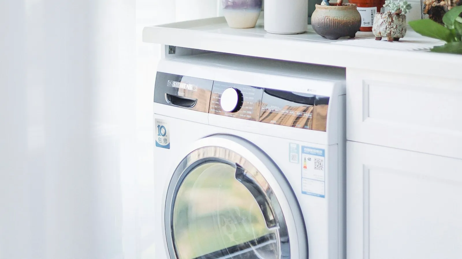 White front-load washing machine beside a counter with plants